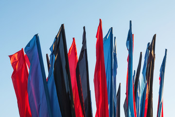 Red, blue, black flags against the blue sky