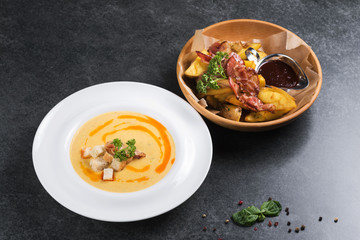 Complex dinner. Fried potatoes with appetizing bacon and sauce are in a wooden plate