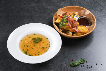 Complex dinner. Fried potatoes with appetizing bacon and sauce are in a wooden plate