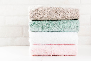 Spa relax and bath concept, stack clean bath towels colorful cotton terry textile in bathroom white...