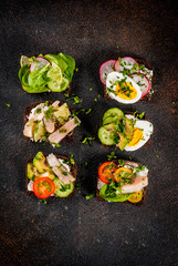 Set of various danish open sandwiches Smorrebrod with fish, egg and fresh vegetables, dark background copy space above