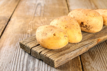 Yellow potato tubers on an old wooden table.