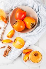 Persimmon fruit smoothie with cinnamon and anise stars, white marble table copy space top view