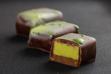 Cut of handmade bonbon with praline and green color ganache (matcha tea or pistachio taste)