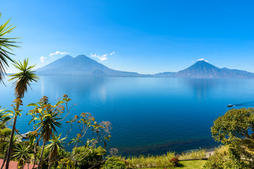 View from Lake Atitlan in the early morning, blue skys and clear water, beautiful magic lake with volcanos and indigenous people in the highland of Guatemala  - Powered by Adobe