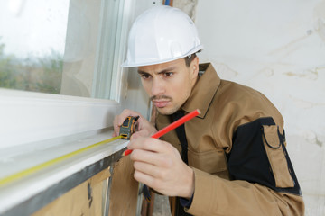 builder measuring the window pane