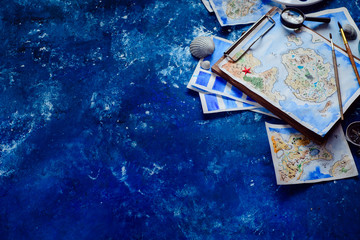 Handpainted fantasy map on a navy blue background with copy space. Artist workplace with watercolor sketches. Creative travel concept.