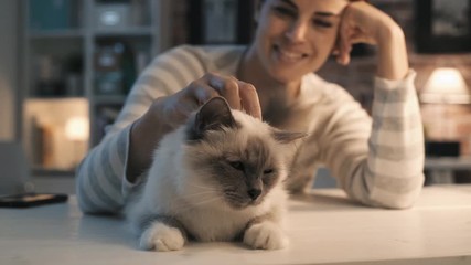 Smiling woman caressing her cat at home