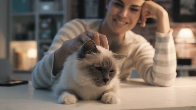 Smiling woman caressing her cat at home