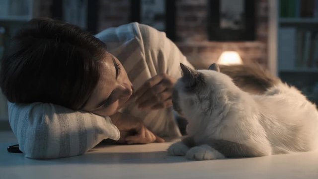 Smiling woman caressing her cat at home