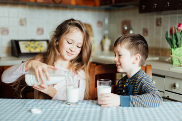 Children drink milk and have fun in the kitchen at the morning