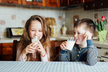 Children drink milk and have fun in the kitchen at the morning