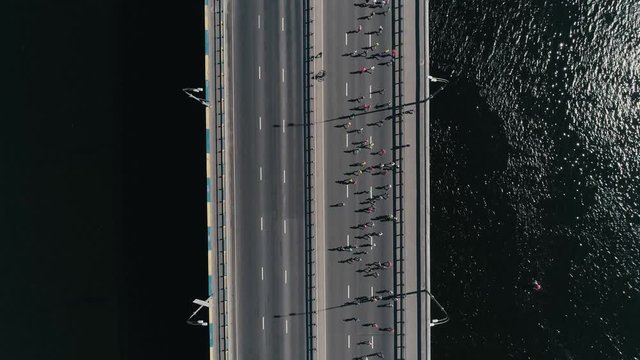 Marathon running on the bridge. Vertical dolly shot top view slow motion