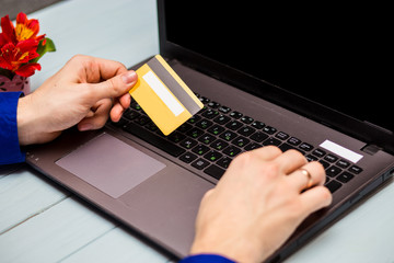 Man hold credit card  in hand and entering security code using laptop keyboard at home. Technology, banking, home, lifestyle and online shopping conceptconcept