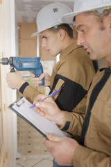 male architect an worker with drill at a building site