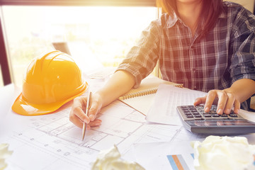 Asian engineer , architect woman using calculator for accounting and analyzing building structure...