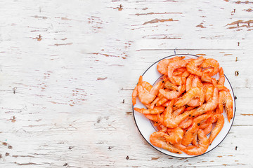 Cooked fresh  shrimps on a white plate over old white wooden table with copy space, flat lay. Seafood healthy food concept