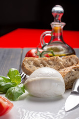 Traditional italian food - white ball mozzarella buffalo Italian soft cheese with cheese knife, tomato, basil, olive oil