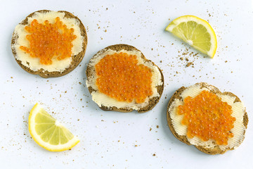 Red caviar sandwiches and lemon. Top view