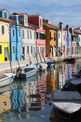 Fototapeta na wymiar Houses of Burano and reflection in the water. Waterways with traditional boats and colorful facade