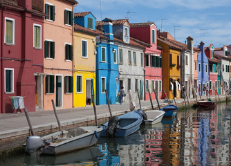Fototapeta na wymiar Houses of Burano and reflection in the water. Waterways with traditional boats and colorful facade