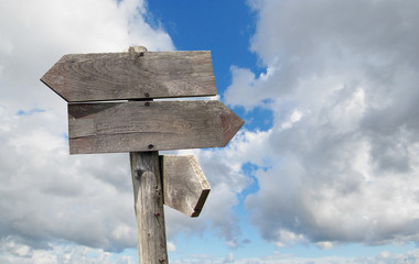 travel destinations options. Direction road sign with wooden arrows on sky and clouds