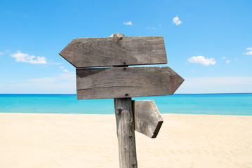 summer travel destinations options. Direction road sign with wooden arrows on beach and sea