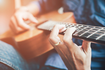 Obraz premium A handsome man playing acoustic guitar.Practicing in playing guitar.