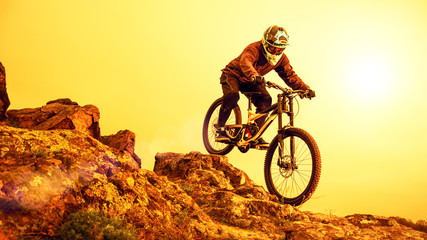 Fototapeta na wymiar Professional Cyclist Riding Mountain Bike Down the Rocky Hill. Extreme Sport and Enduro Biking Concept.