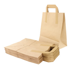 Group of folded and unfolded plain brown paper take away food carrier bags with handles isolated on a white background