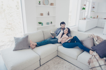 Portrait of stylish attractive couple enjoying reading novel, poem, poetry, lying on sofa in modern...