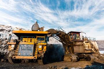 Large quarry dump truck. Loading the rock in dumper. Loading coal into body truck. Production useful minerals. Mining truck mining machinery, to transport coal from open-pit as the Coal Production.