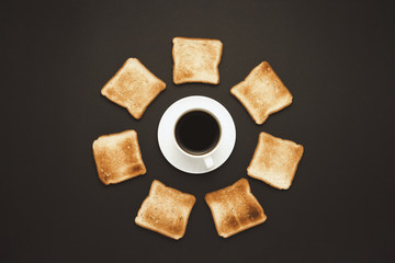 Fototapeta na wymiar White cup with coffee and Toast piled around on a dark background. Flat lay, top view