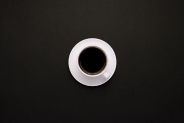 White cup with coffee on a dark background. Minimalistic style. Flat lay, top view