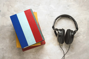 Headphones and a pile of books. The upper book has a cover in the form of a flag of France. Concept audiobooks. Learning languages. French language © Alex
