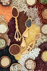 Dried super food background with grains, seeds, pulses & cereals loose and in love spoons. Foods high in omega 3, protein, antioxidants, smart carbohydrates, anthocyanins & fibre. Top view. 