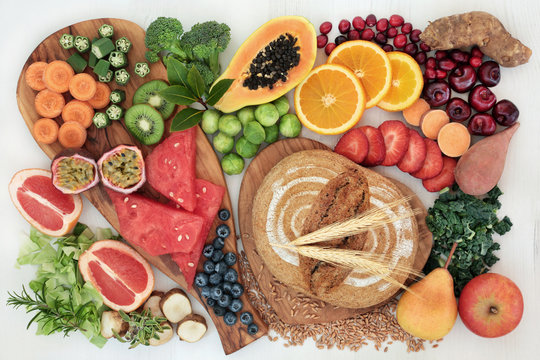 High dietary fibre super food concept with fresh fruit, vegetables, whole grain rye bread, herbs and spices top view on rustic background. Foods high in antioxidants, anthocyanins and vitamins.