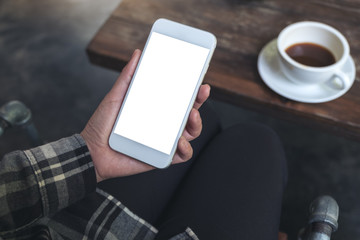 Mockup image of a woman's hand holding white mobile phone with blank desktop screen with coffee cup on wooden table in cafe