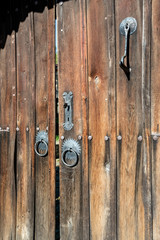 Close up of old double wooden tiled rustic house door to the street in Bulgaria, Rhodope mountain. Decorated with metallic hoops and handles.
