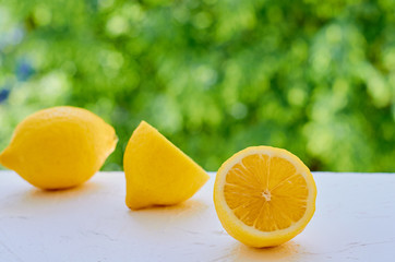 Lemon and slices close up on the blurred nature background with copy space. Citrus yellow texture. Side view