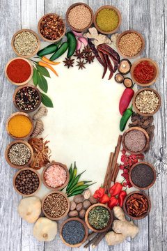 Herb and spice abstract background border with fresh and dried herbs and spices on rustic wood and parchment paper. Top view.