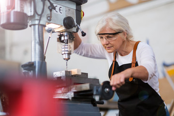 Senior woman doing woodwork in a workshop
