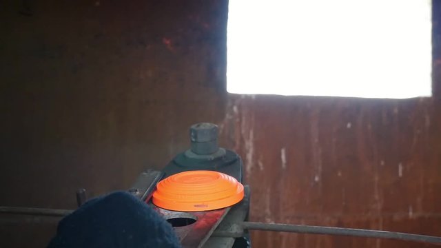 Closeup of a clay target thrower with a person flinging orange clay pigeons on a range through a small window in summer in slow motion