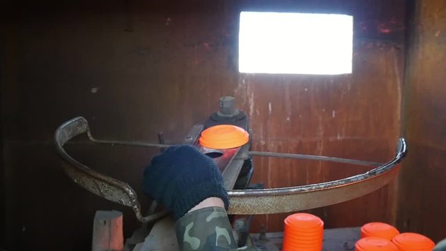 Closeup of a clay pigeon thrower with a man flinging orange clay targets on a range through a small window in summer in slow motion