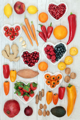 Healthy heart food concept with fruit, vegetables, nuts and spice on distressed wood background. High in antioxidants, omega 3 fatty acids, vitamins, fibre, minerals and anthocyanins.