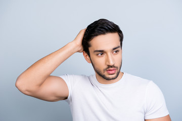 Portrait of manly stunning man in white outfit touching fixing correcting his perfect smooth healthy hair looking to the side isolated on grey background, hair therapy trouble concept
