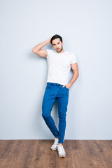 Full size body portrait of stunning brutal man touching his perfect smoth soft healthy hair holding hand in pocket flirting looking at camera standing over grey background