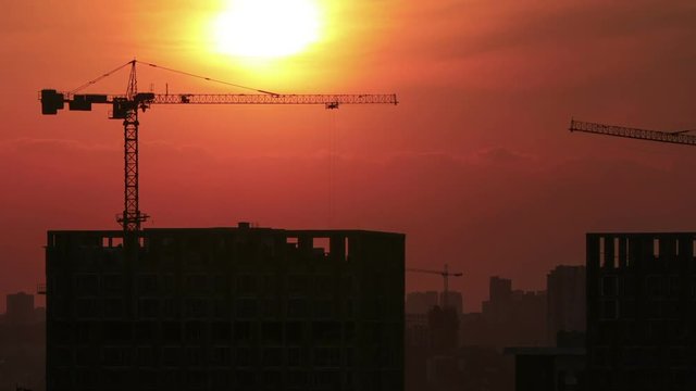 Timelapse of a building crane works at a sunset with beatiful sky color changing from orange to red (1080p)