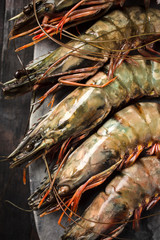 Raw prawns in shells on a stone board, top view.