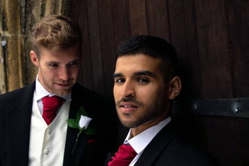 Gay wedding, grooms posing for as they hold hands and kiss outside village church